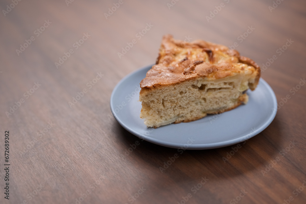 A piece of charlotte apple pie on a saucer on walnut table A piece of charlotte apple pie on a saucer on walnut table