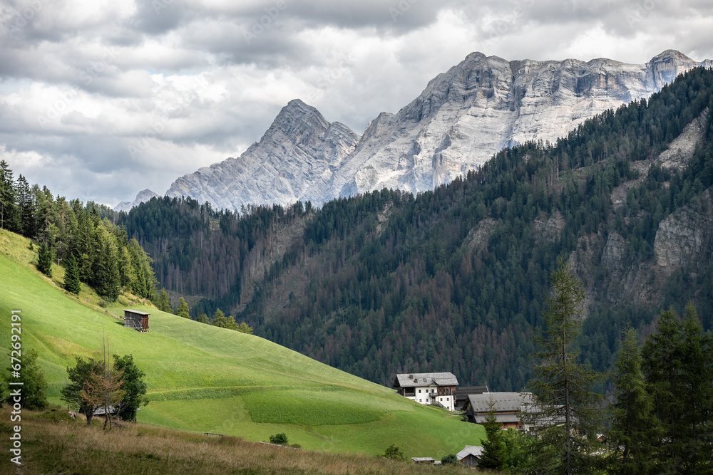 beautiful panoramic landscape of rural village in alta badia south tyrol with cloudy mountains meadow forest and houses