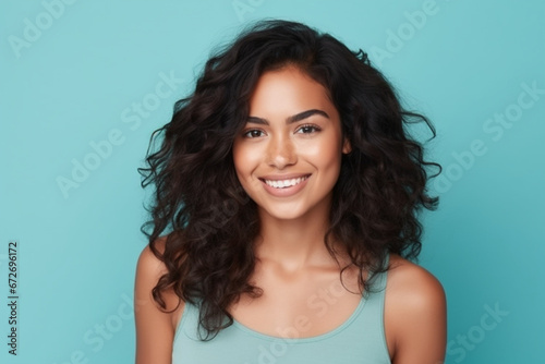 young latina woman smiling looking at camera isolated on turquoise background