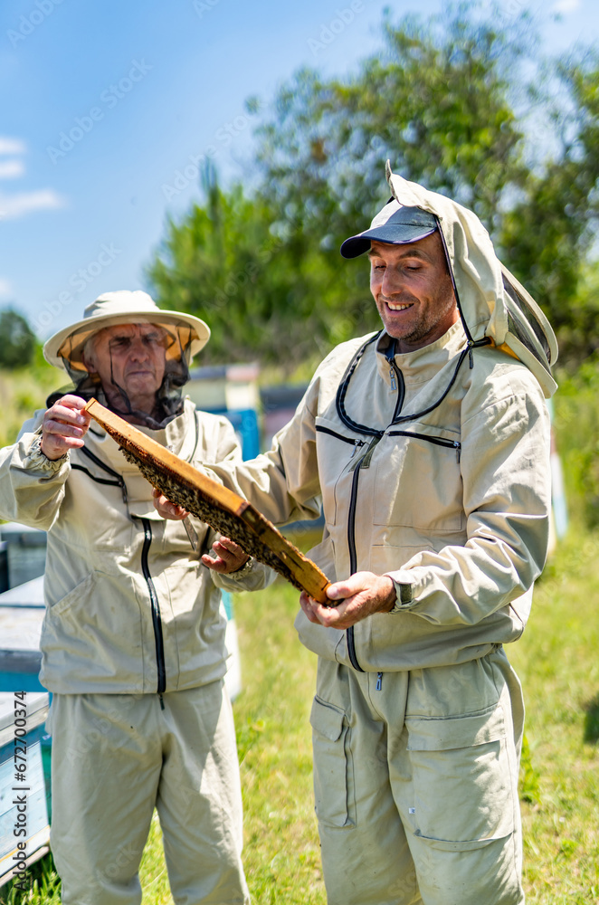 Two Beekeepers in Protective Suits Holding a Beehive. Two men in bee suits holding a beehive
