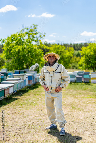 A Beekeeper Amidst a Buzzing Apiary. A man standing in front of a bunch of beehives