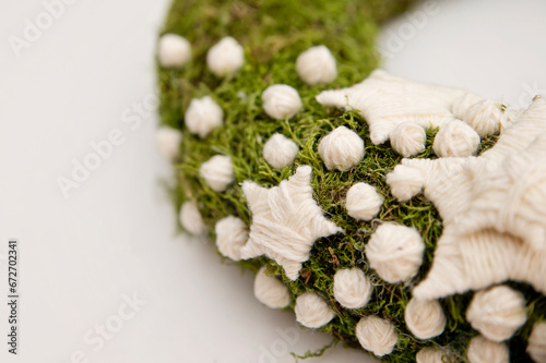 Winter Seasonal celebration. New Year festival. Hand made Christmas wreath made from natural forest moss and hand knitted stars and snow balls. Home decoration. Calendar greeting card.