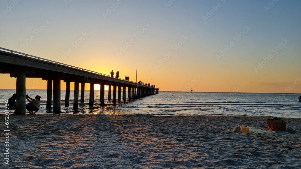 Sandy beach and pier against the background of the sunset.