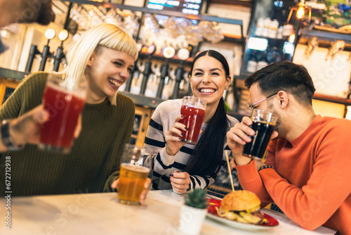 Smiling young friends drinking craft beer in pub