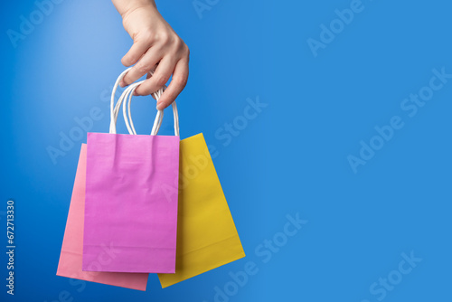 shopping bags in hand on blue background, shopping delivery, gift bags