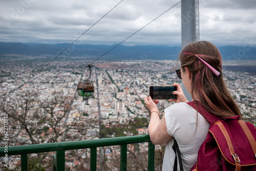Mujer turista tomando fotos desde el mirador del Cerro San Bernardo, en la ciudad de Salta photo
