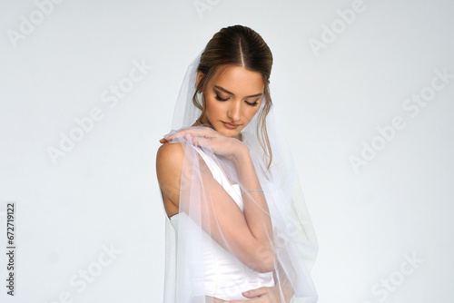 The bride in a white wedding dress with a veil. A girl in a wedding dress. a photo for a wedding salon.