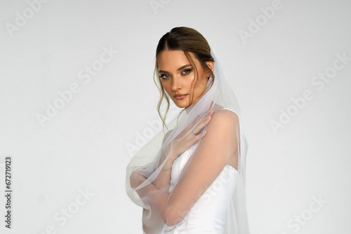 The bride in a white wedding dress with a veil. A girl in a wedding dress. a photo for a wedding salon.