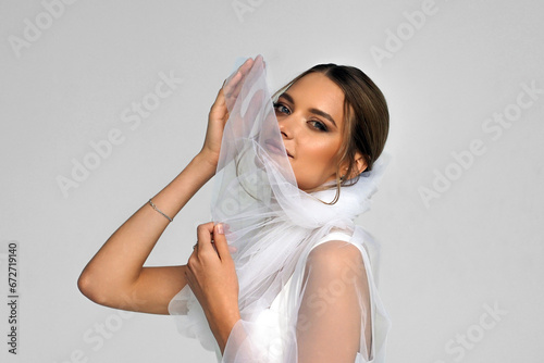 The bride in a white wedding dress with a veil. A girl in a wedding dress. a photo for a wedding salon.