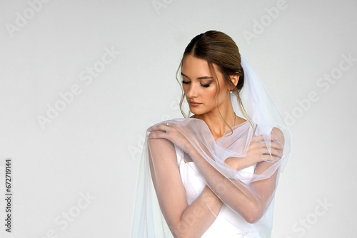 The bride in a white wedding dress with a veil. A girl in a wedding dress. a photo for a wedding salon.