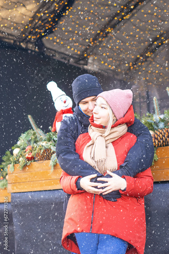 Happy girl and boy hugging in front of Christmas decoration in winter at a snow day.