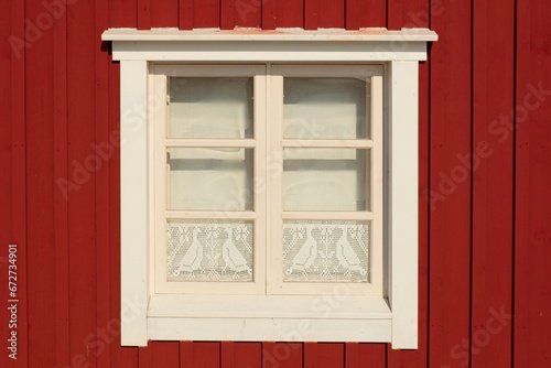 White frame window on the facade of a red painted building.