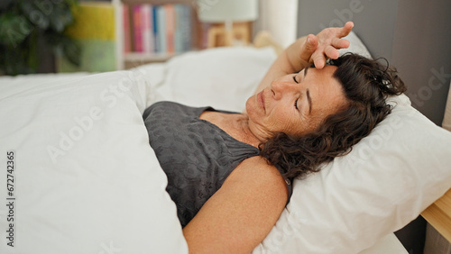 Middle age hispanic woman lying on bed sleeping at bedroom