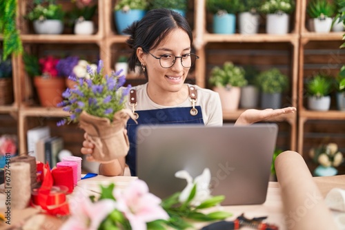 Young hispanic woman working at florist shop doing video call pointing aside with hands open palms showing copy space, presenting advertisement smiling excited happy © Krakenimages.com