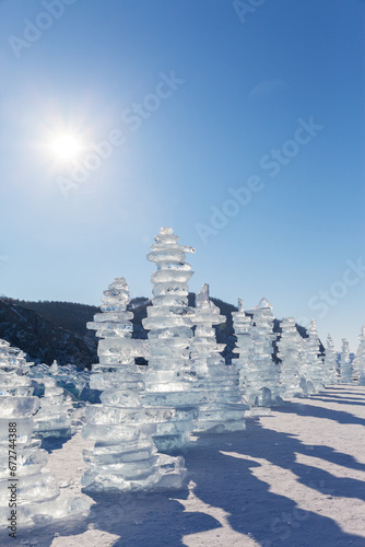 Baikal Lake on cold sunny winter day. Row of traditional high ice pyramids made of transparent ice floes left by tourists near famous Cape Khoboy on Olkhon Island. Winter travel and outdoor recreation © Katvic