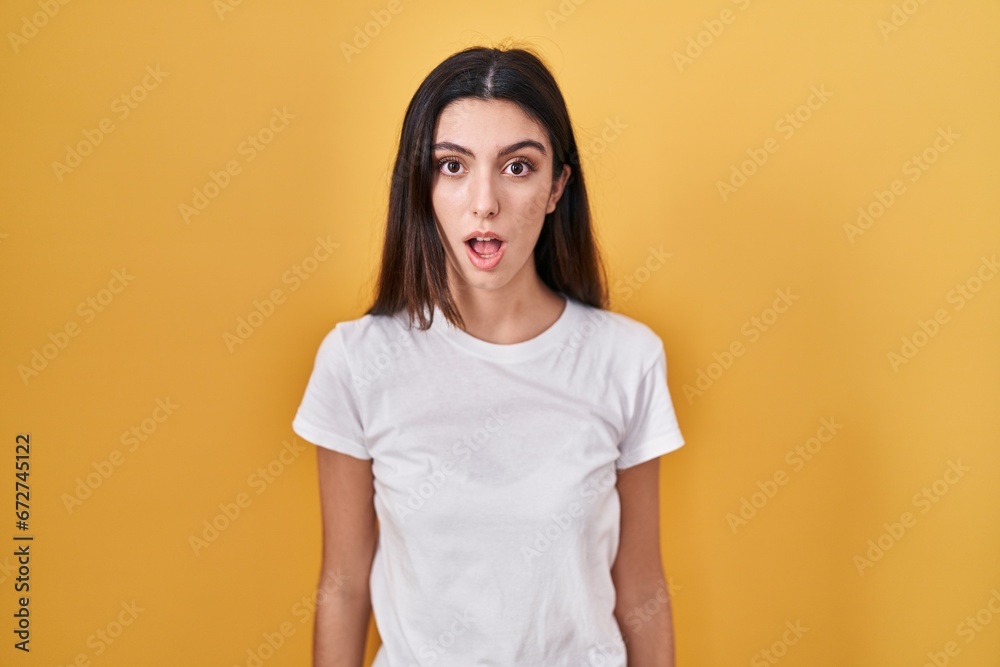 Obraz premium Young beautiful woman standing over yellow background afraid and shocked with surprise and amazed expression, fear and excited face.