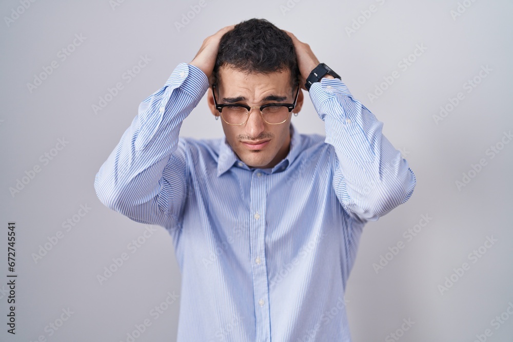 Handsome hispanic man wearing business clothes and glasses suffering from headache desperate and stressed because pain and migraine. hands on head. Handsome hispanic man wearing business clothes and glasses suffering from headache desperate and stressed because pain and migraine. hands on head.