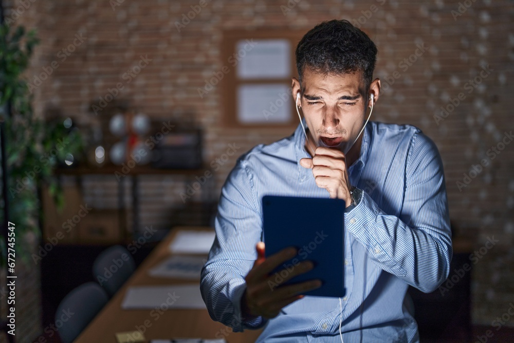 Handsome hispanic man working at the office at night feeling unwell and coughing as symptom for cold or bronchitis. health care concept. Handsome hispanic man working at the office at night feeling unwell and coughing as symptom for cold or bronchitis. health care concept.