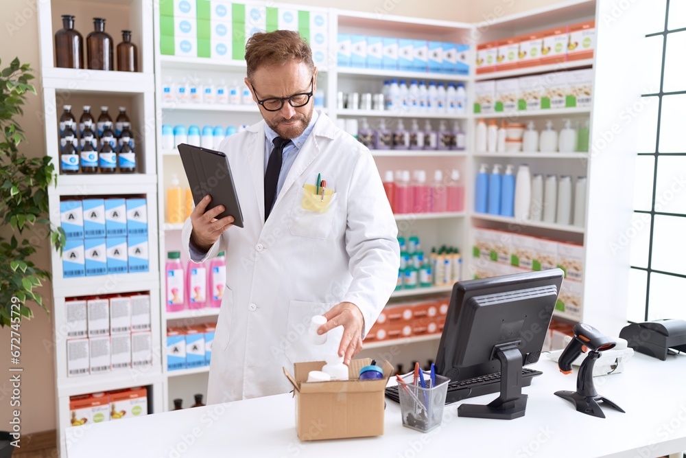 Middle age man pharmacist using touchpad holding pills bottle at pharmacy
