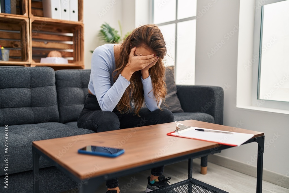 Young beautiful hispanic woman stressed sitting on sofa at home