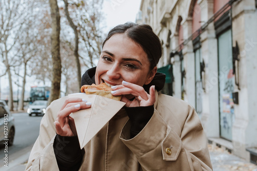 Canvas Print hispanic woman eating delicious crepes in the streets of Paris city, hands holdi