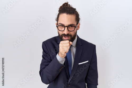 Hispanic man with beard wearing suit and tie feeling unwell and coughing as symptom for cold or bronchitis. health care concept.