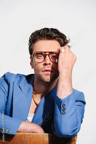 Fashionable man in 90s clothes and eyeglasses looking at camera isolated on grey 