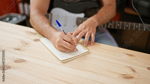 Young latin man musician composing song playing electrical guitar at music studio