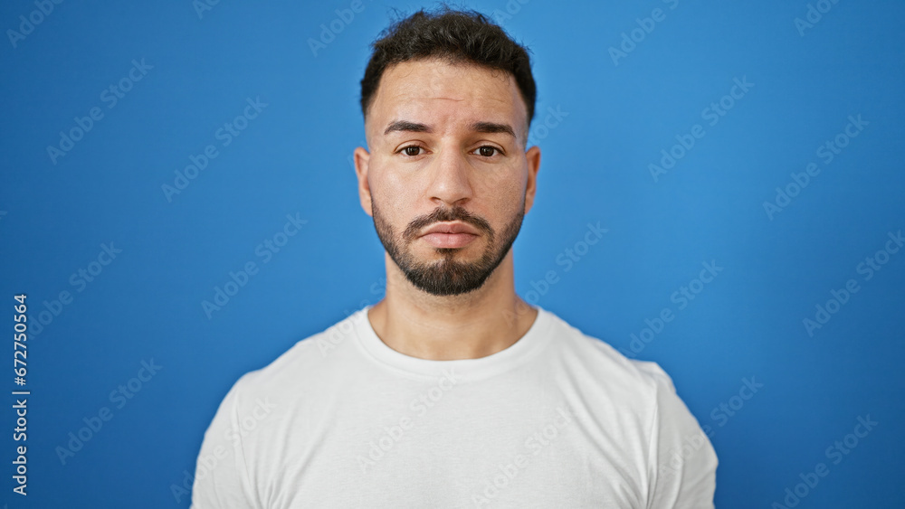 Fototapeta premium Young arab man standing with serious expression over isolated blue background