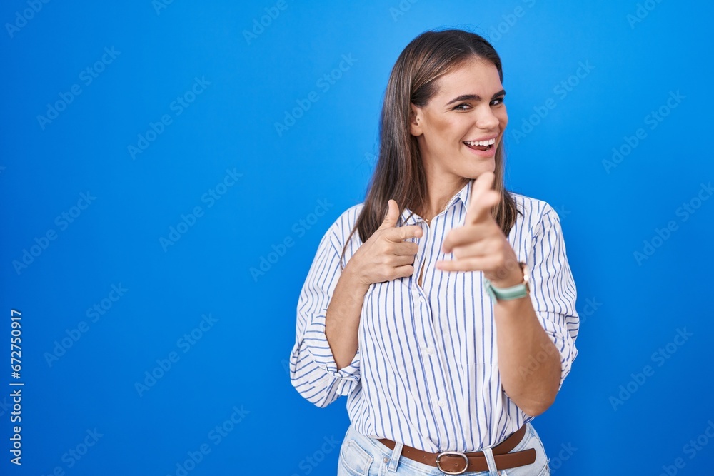 Hispanic young woman standing over blue background pointing fingers to camera with happy and funny face. good energy and vibes. Hispanic young woman standing over blue background pointing fingers to camera with happy and funny face. good energy and vibes.