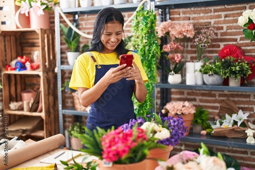 Young beautiful latin woman florist smiling confident using smartphone at florist