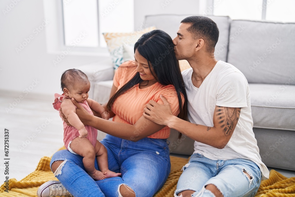 Hispanic family hugging each other sitting on sofa at home