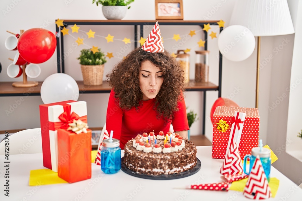 Young hispanic woman celebrating birthday blowing out candles at home Young hispanic woman celebrating birthday blowing out candles at home