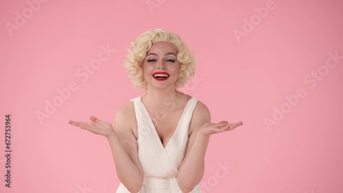 Young woman makes a victory gesture in excitement, celebrating her triumph. A woman in the look of in the studio on a pink background. photo