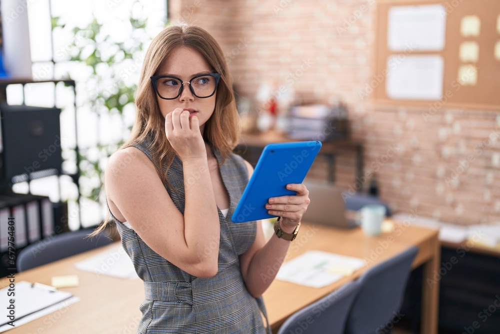 Caucasian woman working at the office wearing glasses looking stressed and nervous with hands on mouth biting nails. anxiety problem. Caucasian woman working at the office wearing glasses looking stressed and nervous with hands on mouth biting nails. anxiety problem.