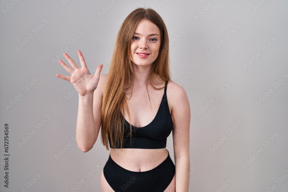 Young caucasian woman wearing lingerie showing and pointing up with fingers number five while smiling confident and happy. Young caucasian woman wearing lingerie showing and pointing up with fingers number five while smiling confident and happy.