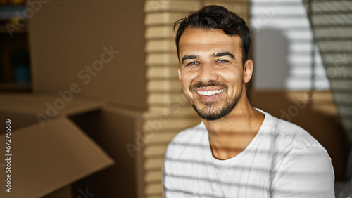 Young hispanic man smiling confident sitting on sofa at new home