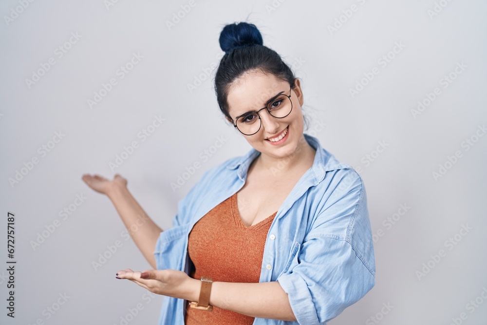 Young modern girl with blue hair standing over white background inviting to enter smiling natural with open hand