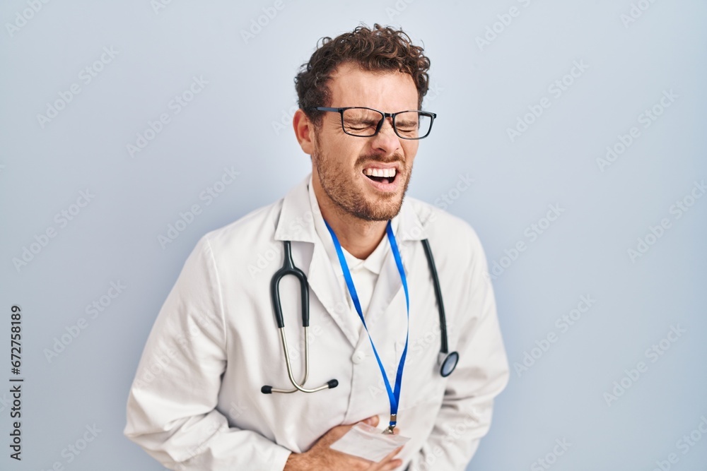 Young hispanic man wearing doctor uniform and stethoscope with hand on stomach because nausea, painful disease feeling unwell. ache concept. Young hispanic man wearing doctor uniform and stethoscope with hand on stomach because nausea, painful disease feeling unwell. ache concept.