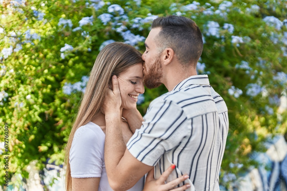 Man and woman couple hugging each other kissing at park