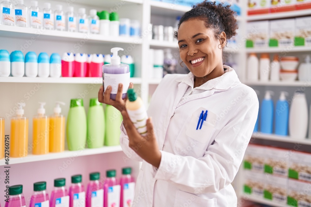 African american woman pharmacist smiling confident holding gel bottles at pharmacy African american woman pharmacist smiling confident holding gel bottles at pharmacy
