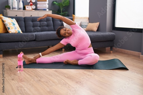 African american woman smiling confident stretching leg at home