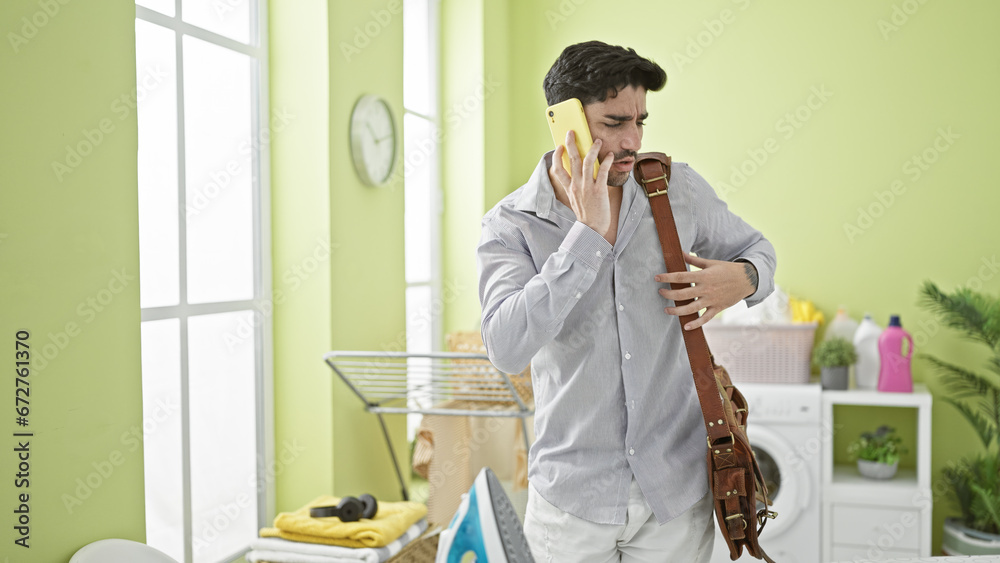 Young hispanic man business worker talking on smartphone at laundry room