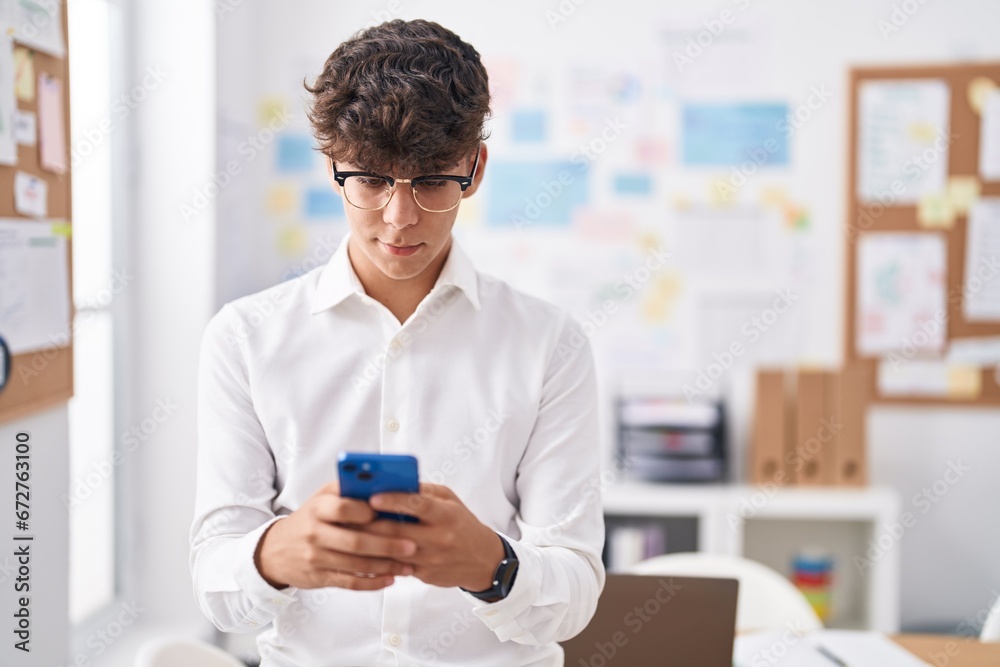 Young hispanic teenager business worker using smartphone at office