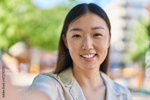 Chinese woman smiling confident making selfie by camera at park