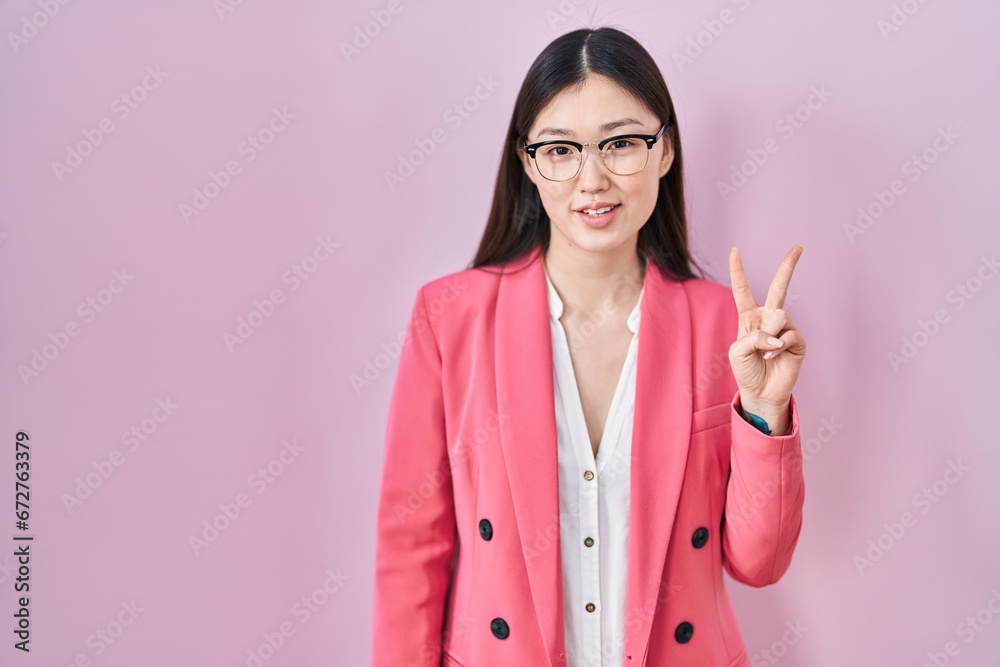Chinese business young woman wearing glasses showing and pointing up with fingers number two while smiling confident and happy. Chinese business young woman wearing glasses showing and pointing up with fingers number two while smiling confident and happy.