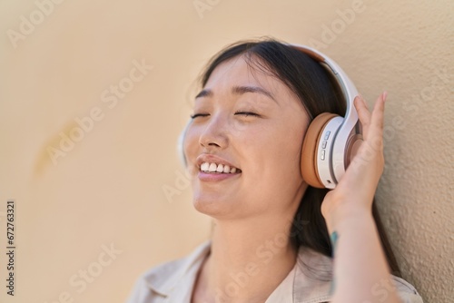 Chinese woman smiling confident listening to music over white isolated background