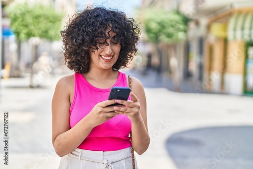 Young middle eastern woman smiling confident using smartphone at street