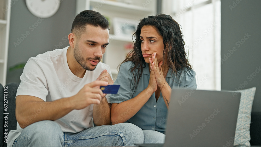 Man and woman couple shopping with laptop and credit card sitting on sofa at home Man and woman couple shopping with laptop and credit card sitting on sofa at home