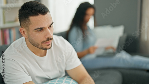 Man and woman couple sitting on sofa looking upset while girlfriend work at home © Krakenimages.com